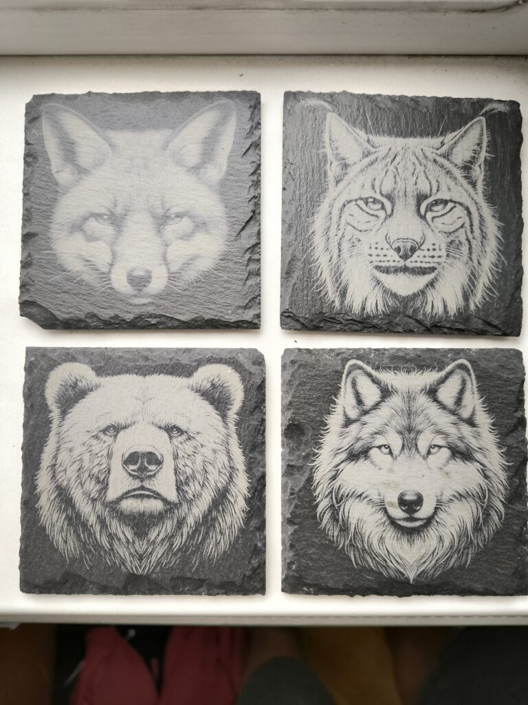 black and white images of animals engraved on slate coasters