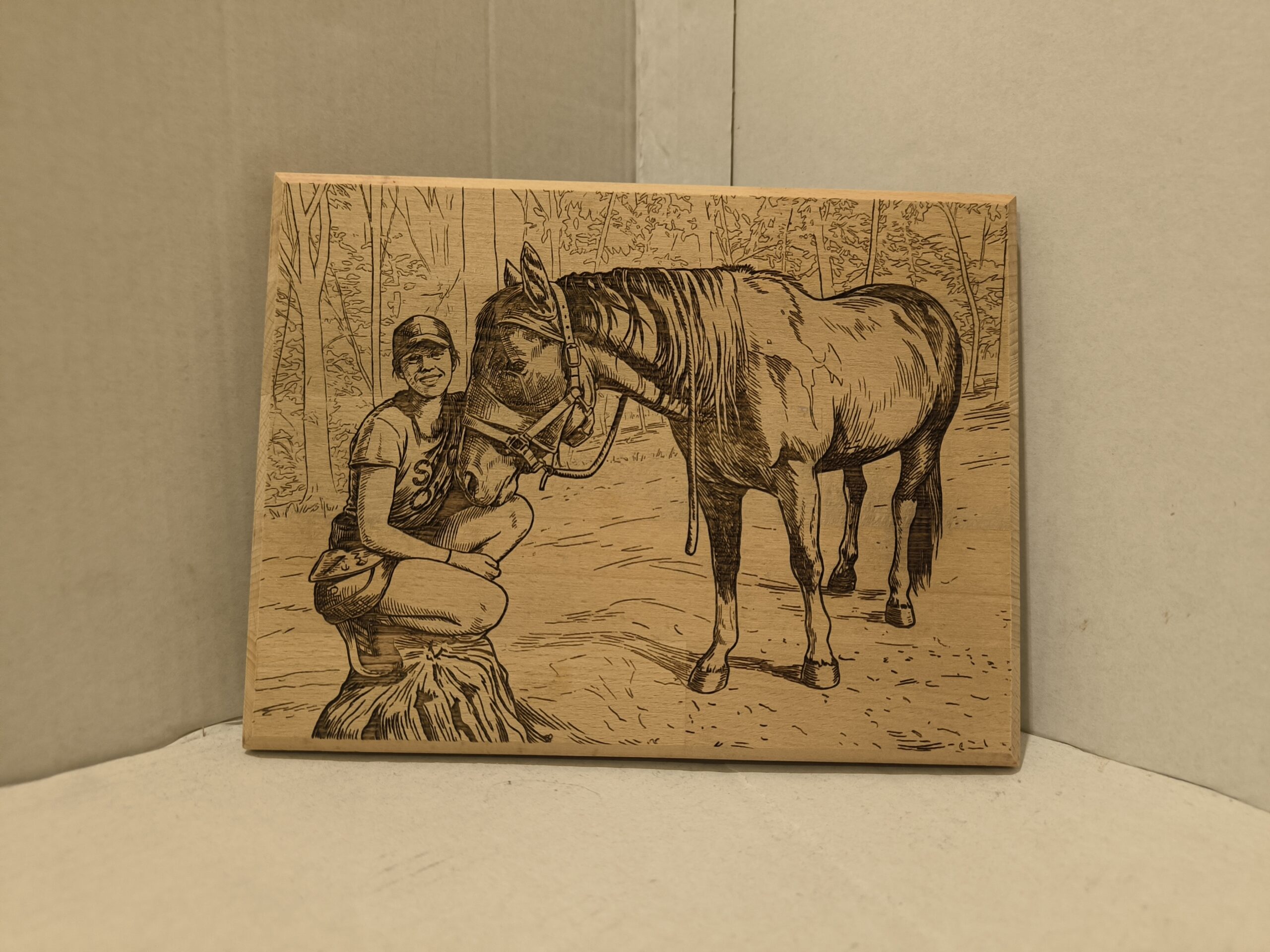 wooden picture of a woman sitting next to her horse