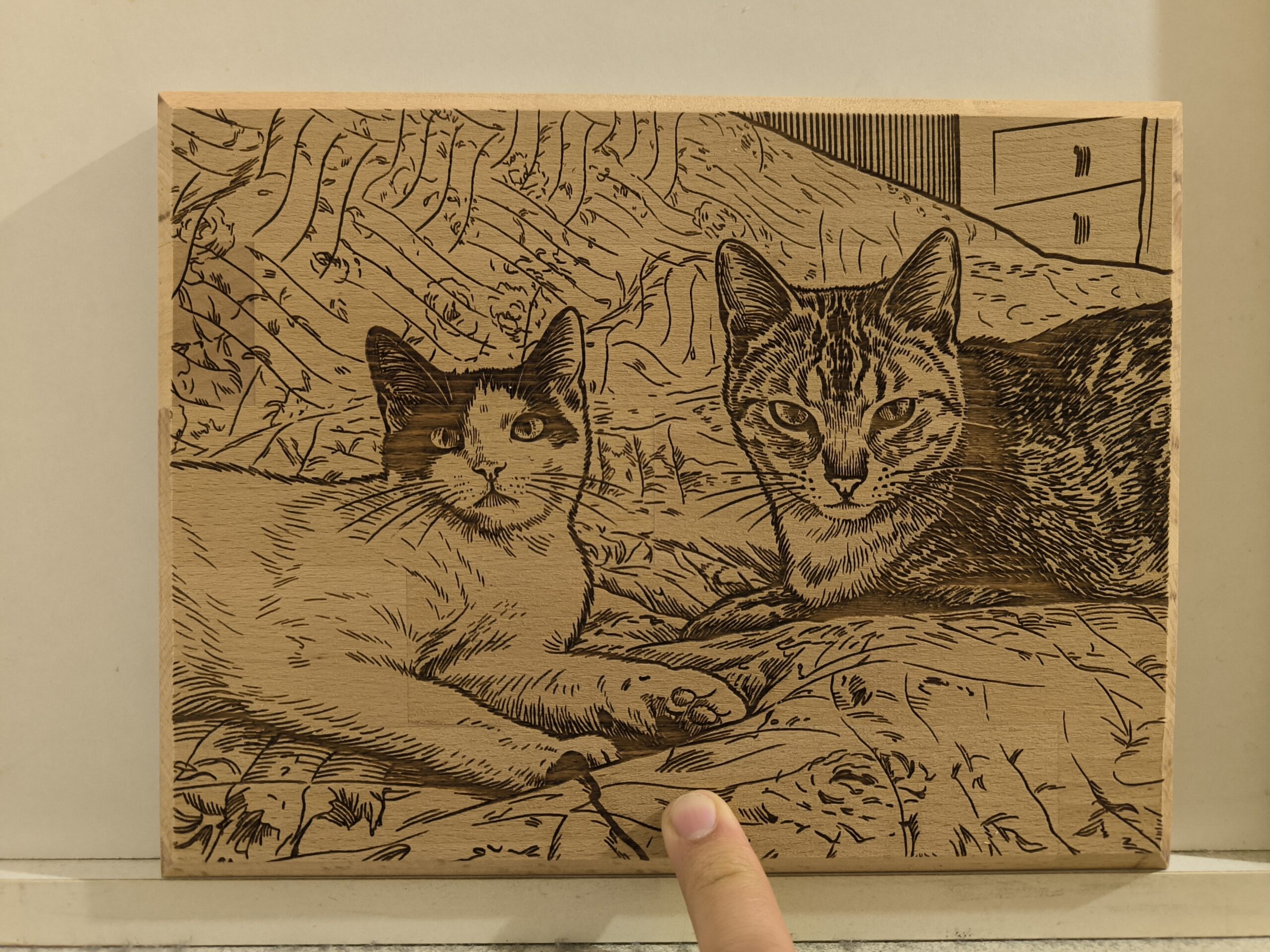 wooden picture of two cats in bed